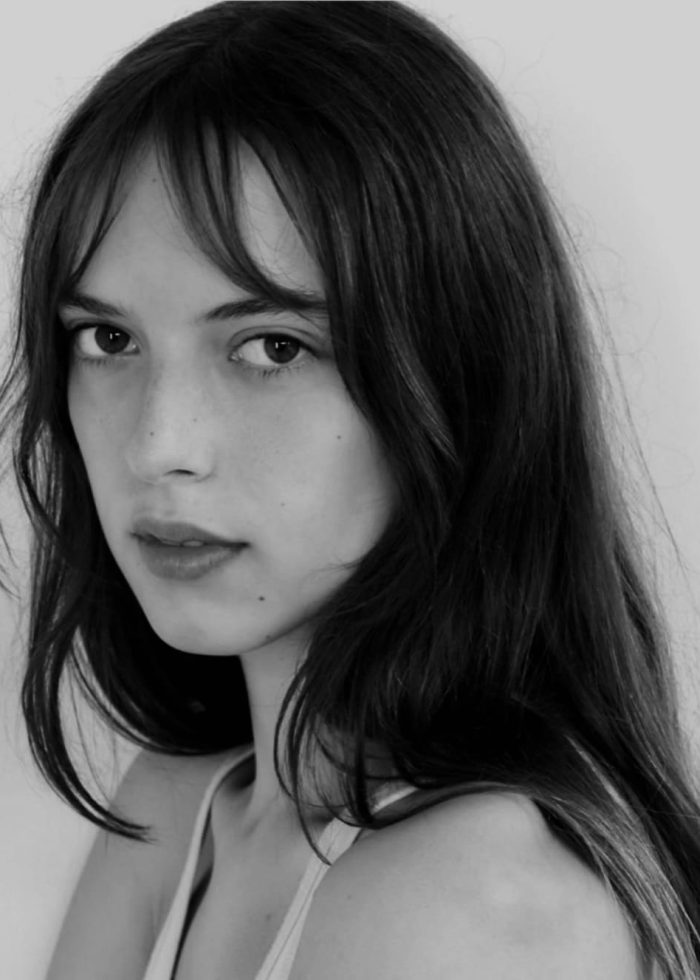 Portrait of a young woman with long hair and bangs, looking directly at the camera.