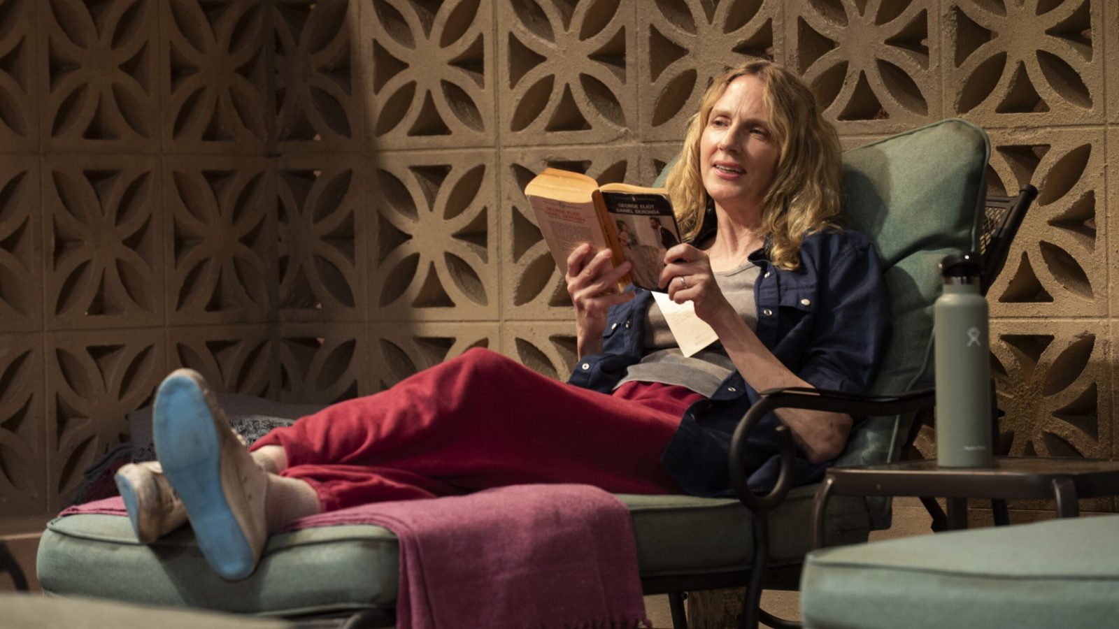 Woman relaxing in a patio chair, reading "Daniel Deronda" by George Eliot.