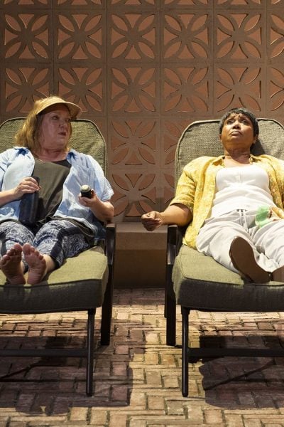 Two women relax in lounge chairs, holding hands. Enjoying infinite life's simple pleasures.