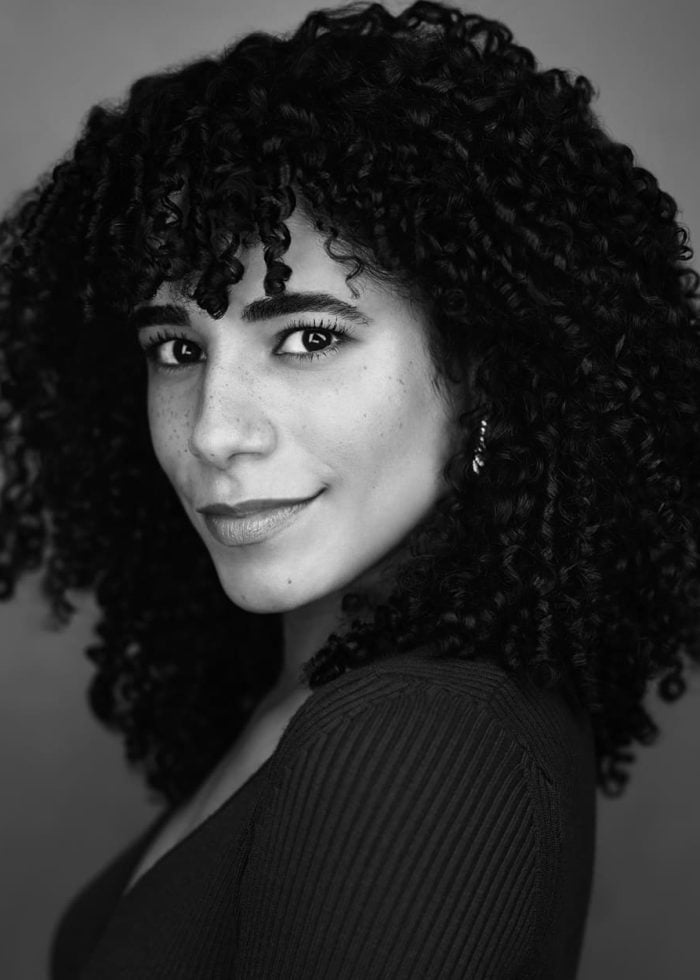 Ilda Mason with curly hair smiles in a black and white portrait