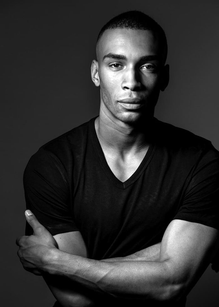 Julian Elijah Martinez in a black v-neck shirt, looking directly at the camera.