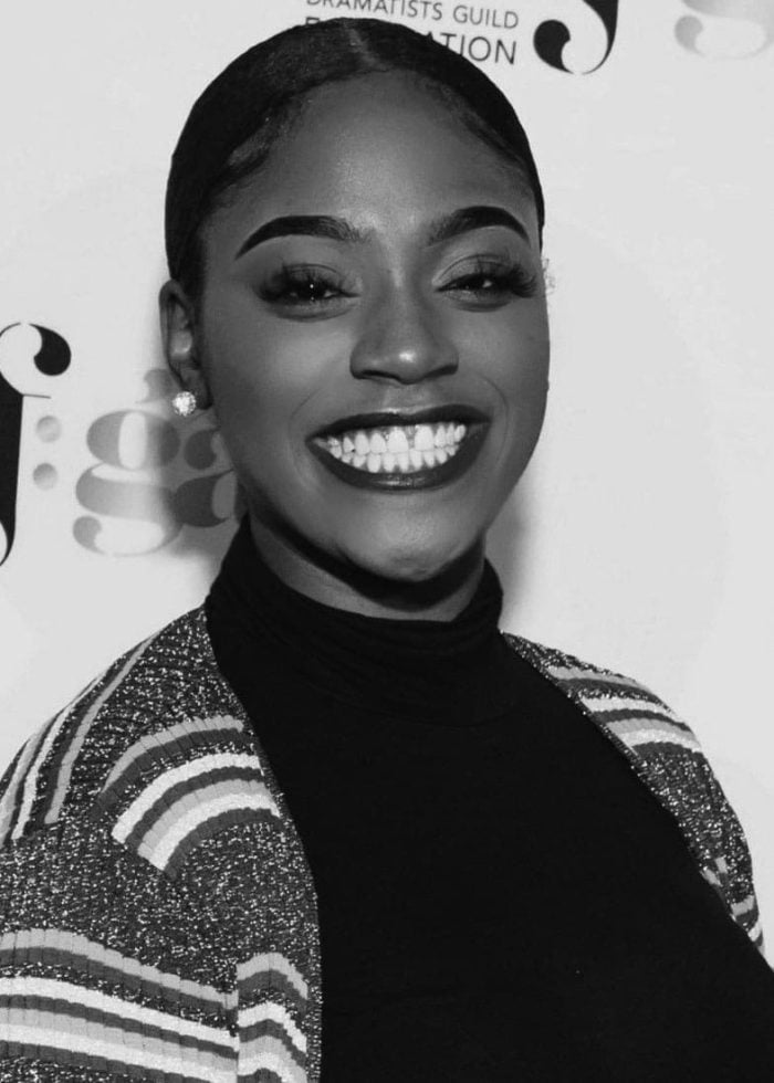 Jai’Len Josey smiling with a dark lip and striped jacket