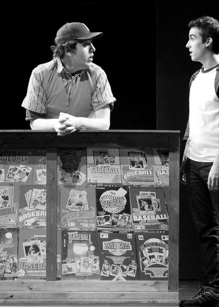 Two actors in a scene from Jackie and Me at Atlantic For Kids, one behind a baseball card counter, the other in front.