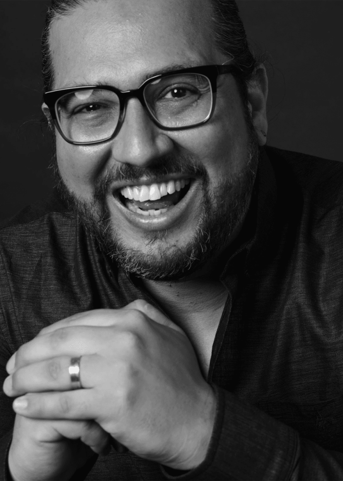 Jaime Lozano smiling, wearing glasses, and clasping his hands