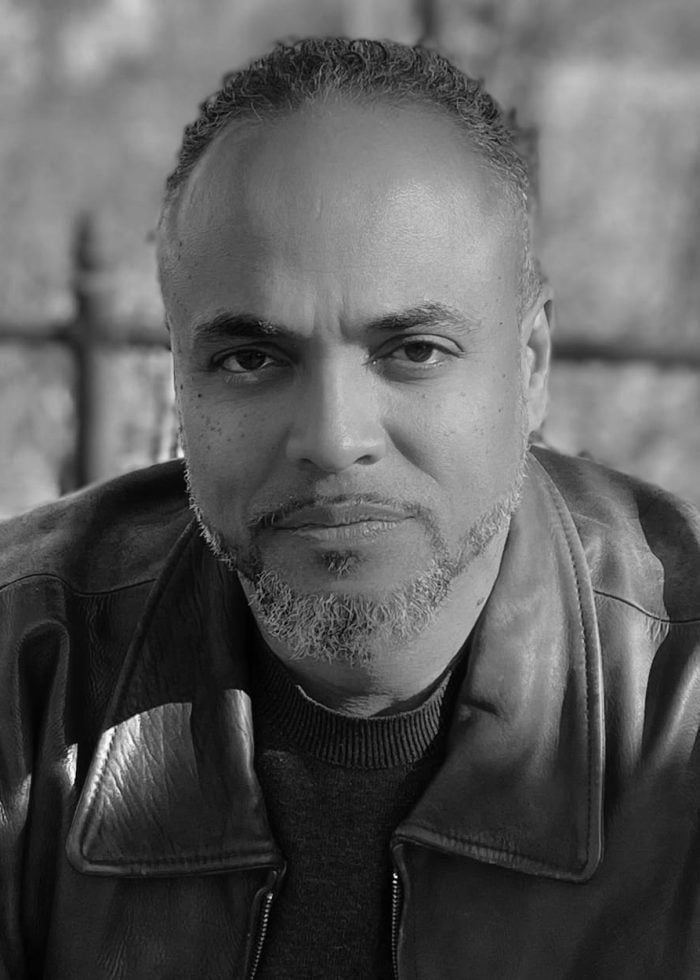 Jainardo Batista Sterling, a man with graying hair and a leather jacket, looking directly at the camera.