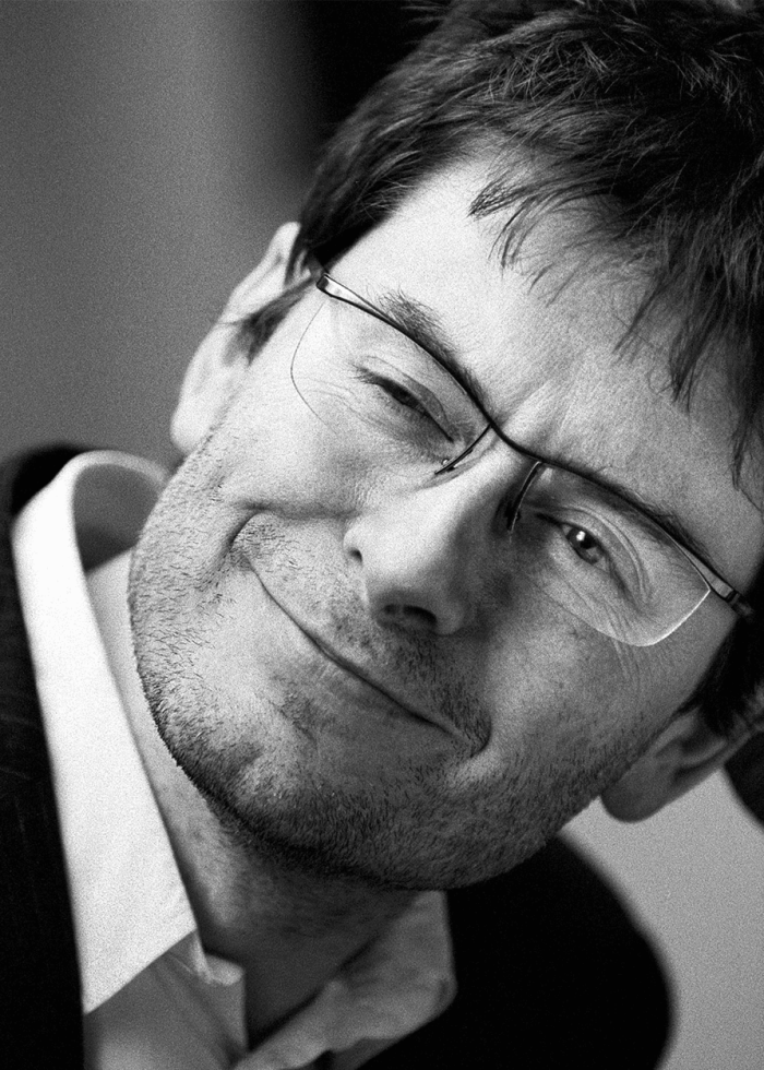 James Macdonald winking, wearing glasses, in black and white portrait