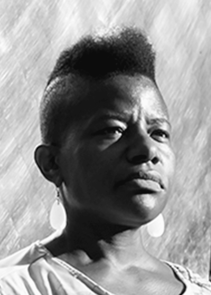 Jennifer Nikki Kidwell with short, textured hair and earrings, looking contemplative.