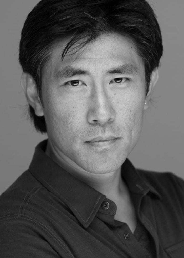 Jinn S. Kim, actor, posing for a headshot in a dark shirt