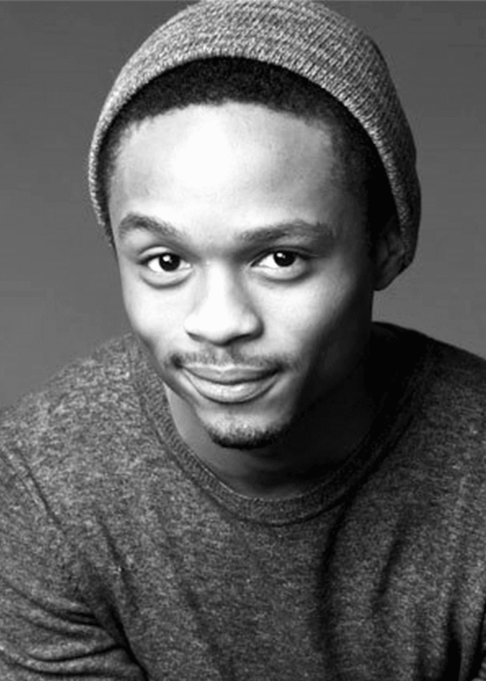 John-Michael Lyles smiling in a gray beanie and sweater