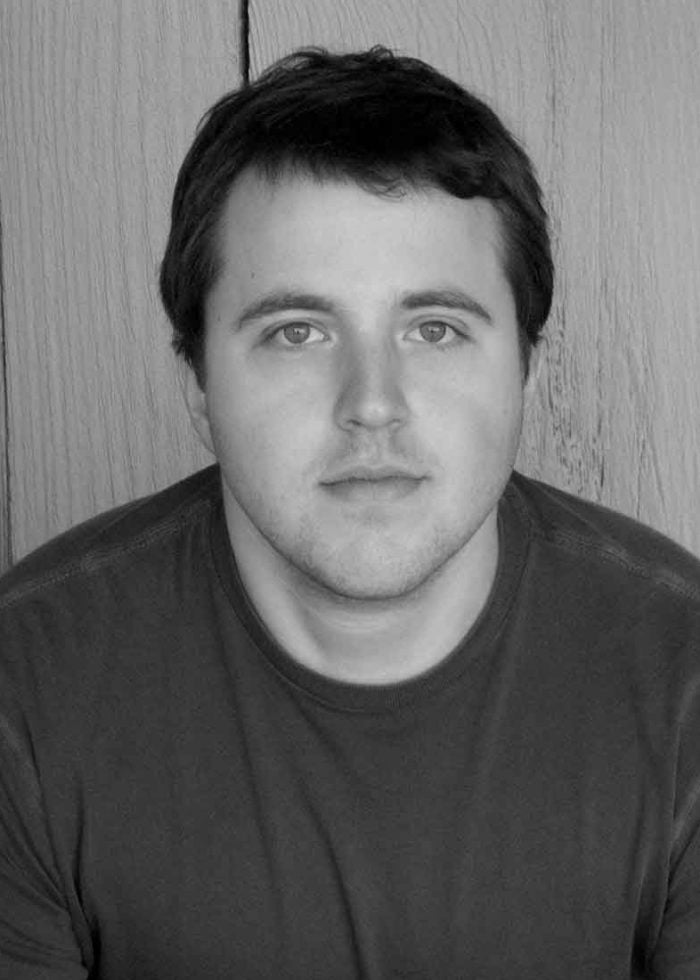 Portrait of Joshua Harmon, looking directly at the camera, in a simple setting.