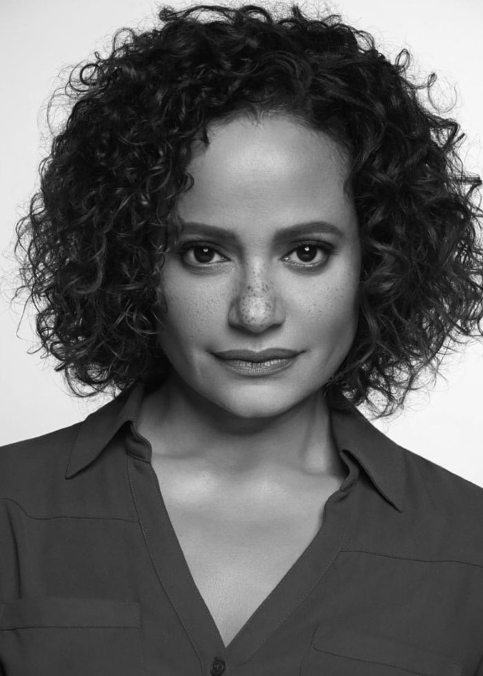 Judy Reyes, actress, in a black and white headshot with curly hair and freckles.