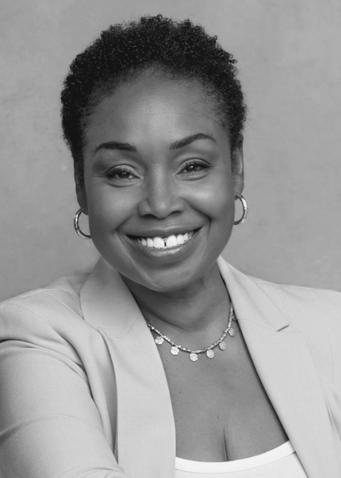 Juliette Jeffers smiling in a blazer, wearing hoop earrings and a necklace.