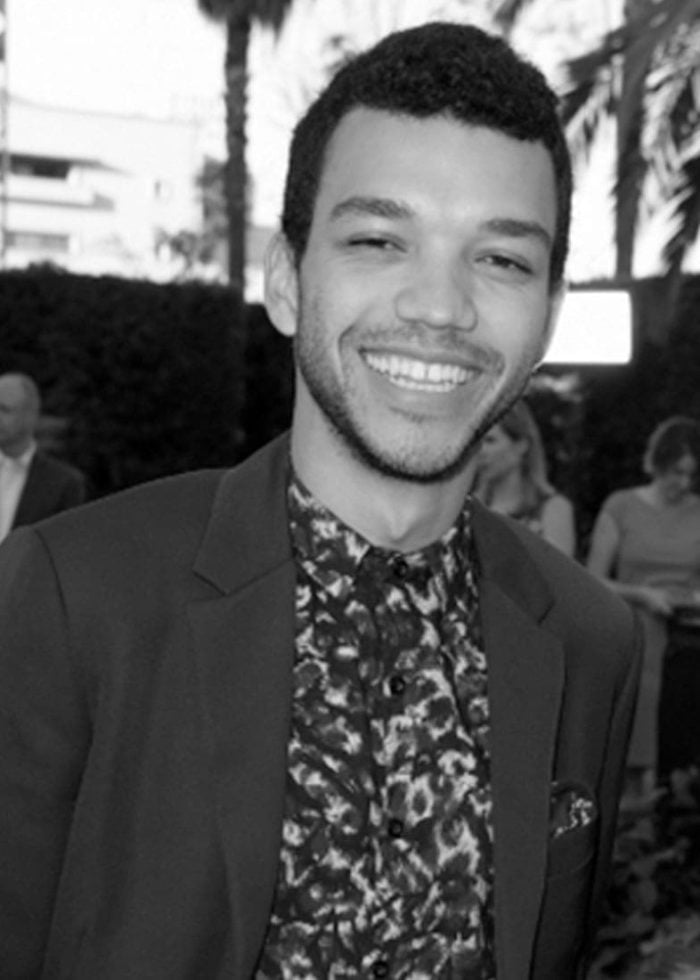 Justice Smith smiling in a dark suit and patterned shirt