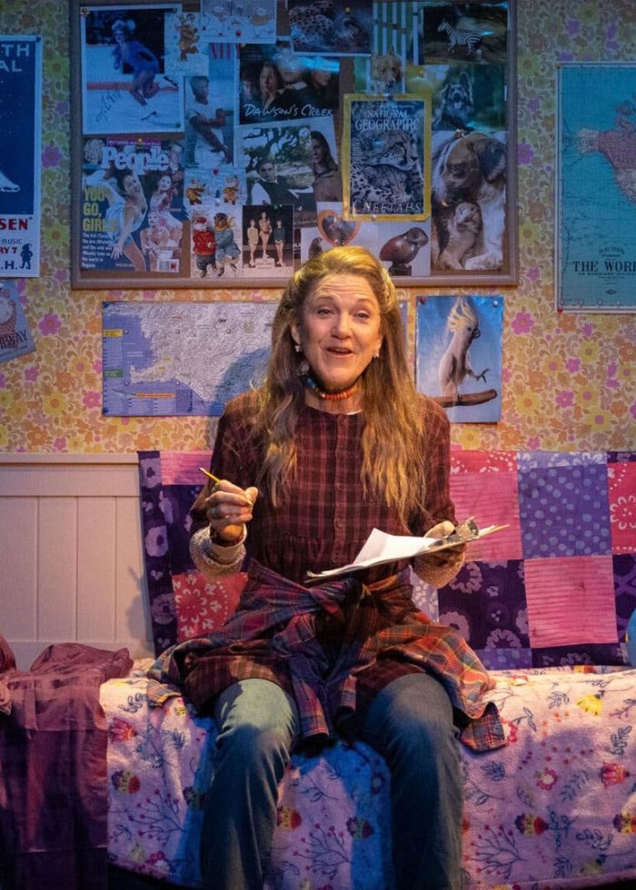 Kimberly Akimbo stage production: Woman on bed in a cluttered bedroom with "Critics' Pick" logo.