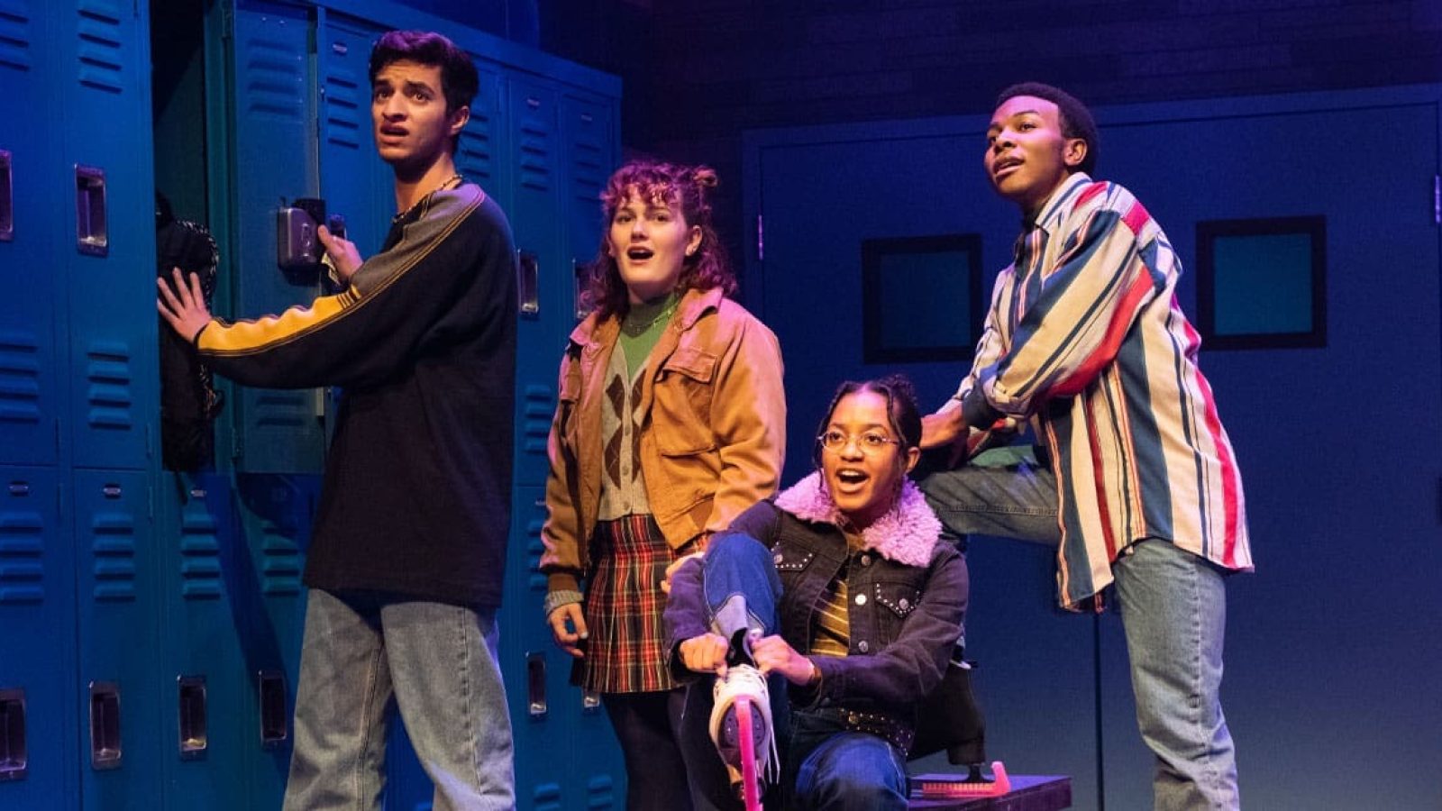 Four actors in 90s-style clothing pose in a school hallway set for the musical Kimberly Akimbo.
