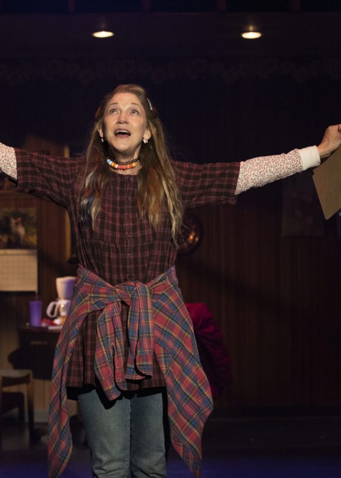 Actress in Kimberly Akimbo play on stage, arms outstretched in performance.