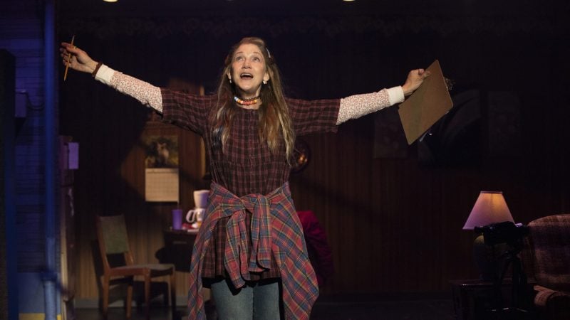 Actress in Kimberly Akimbo play on stage, arms outstretched in performance.