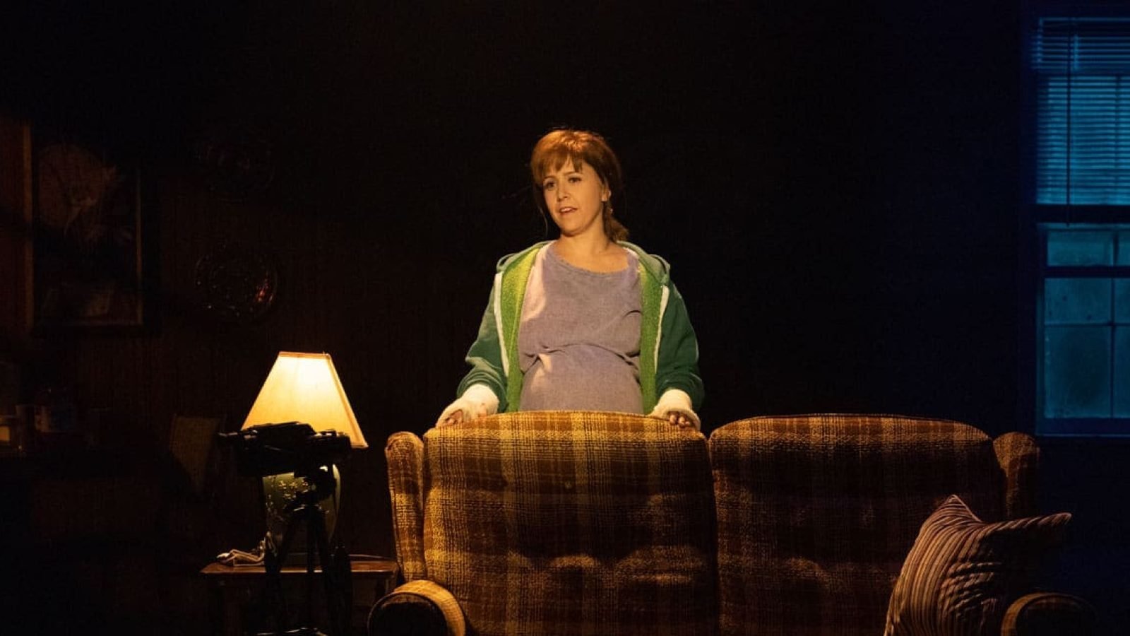 Pregnant Kimberly Akimbo actress stands behind a couch.