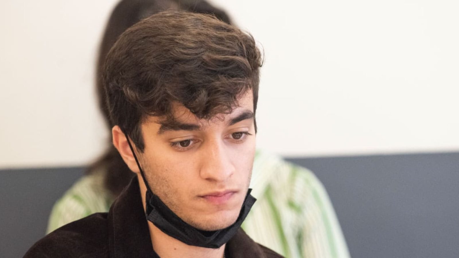 Close-up of a young man wearing a face mask, appearing thoughtful.
