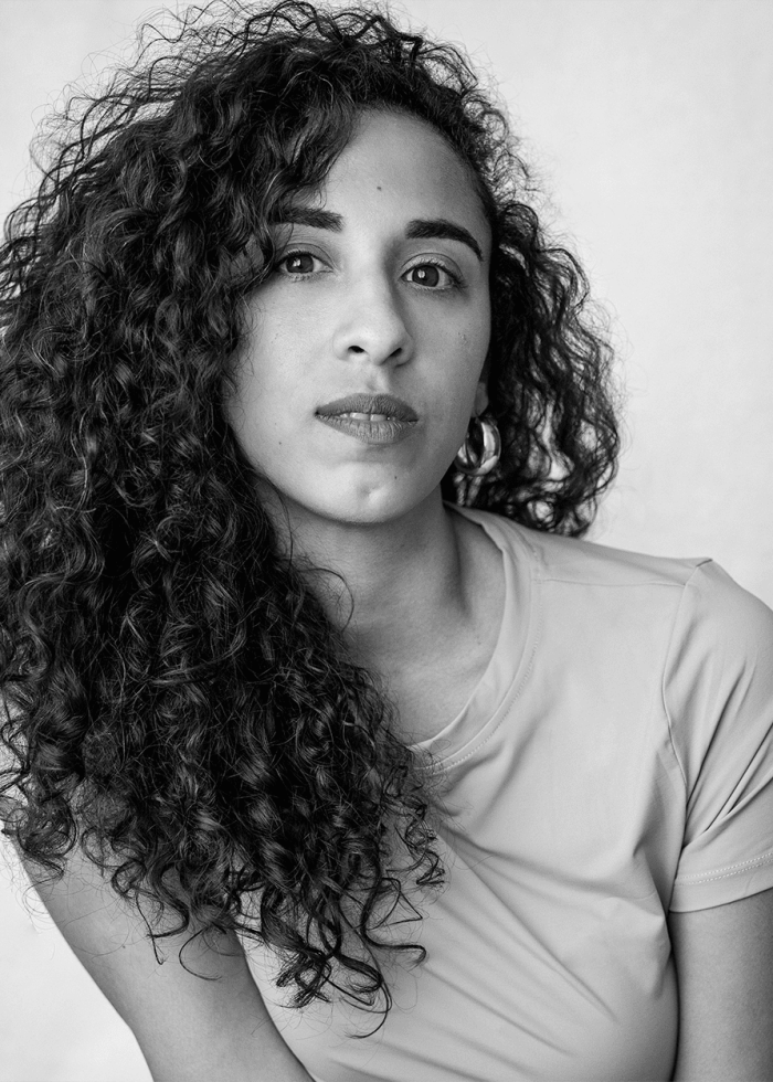 Karina Billini portrait with curly hair, looking directly at the camera