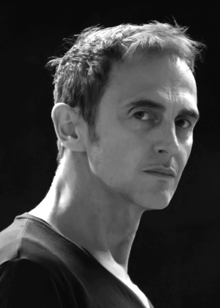 Close-up portrait of a man with short hair looking intently at the camera.