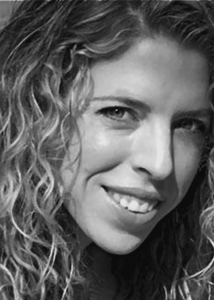 Kristin Hanggi smiling with curly hair, looking at the camera.