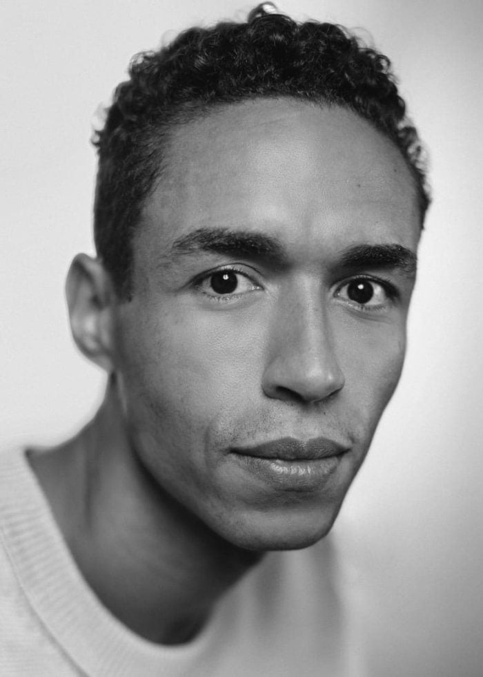 Headshot of Kyle Beltran, looking at the camera in black and white.