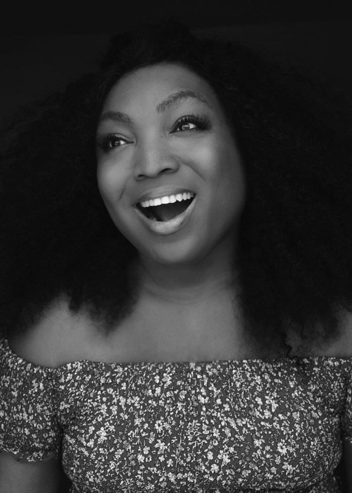 L Morgan Lee smiles, wearing an off-the-shoulder floral top.