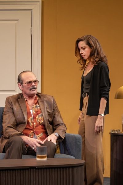 Aubrey Plaza and Liev Schreiber in a scene from "Let's Love!" on stage, dramatic lighting and retro set design.
