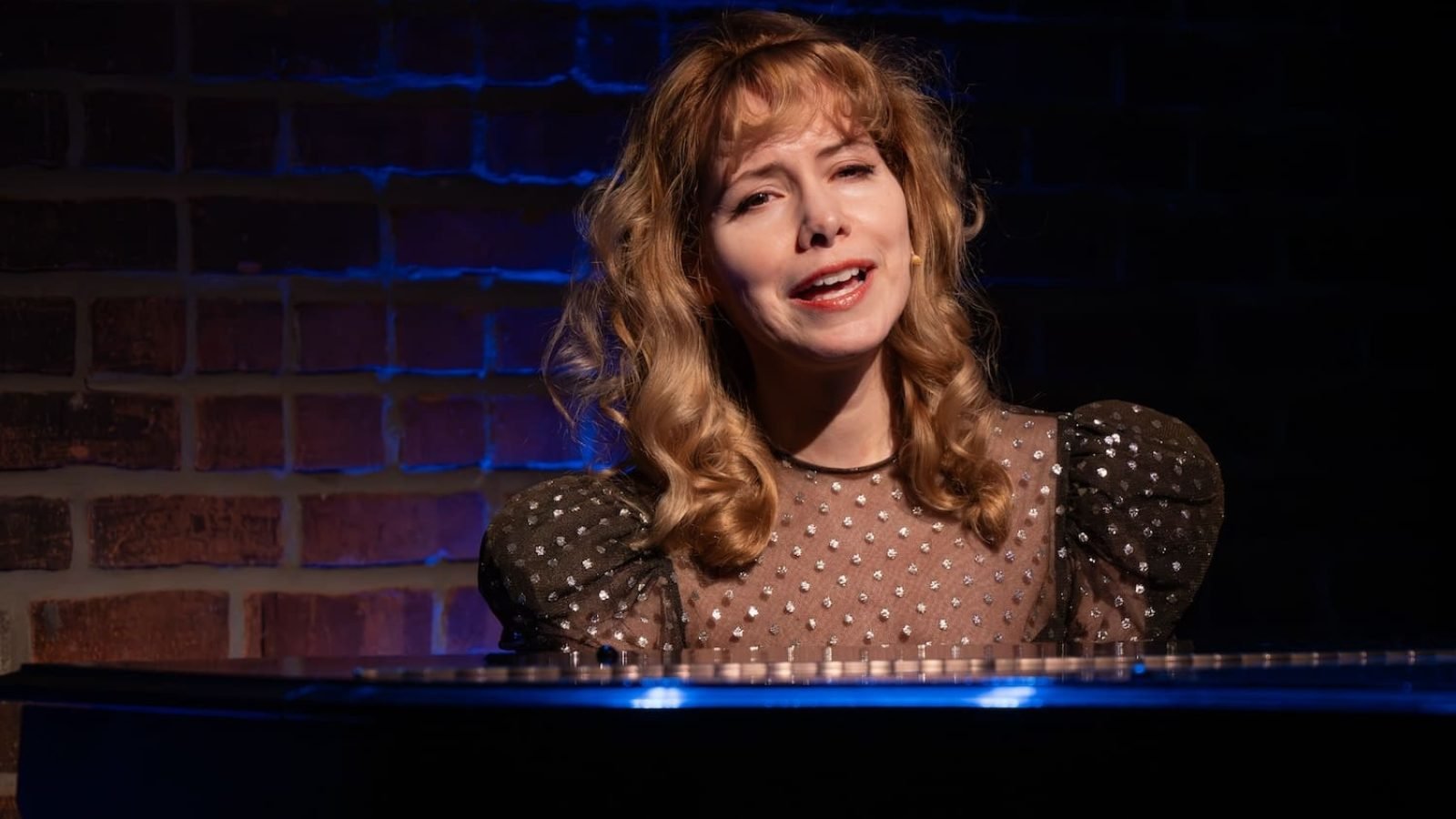 Singer at piano, performing live in concert. “Let’s Love!”