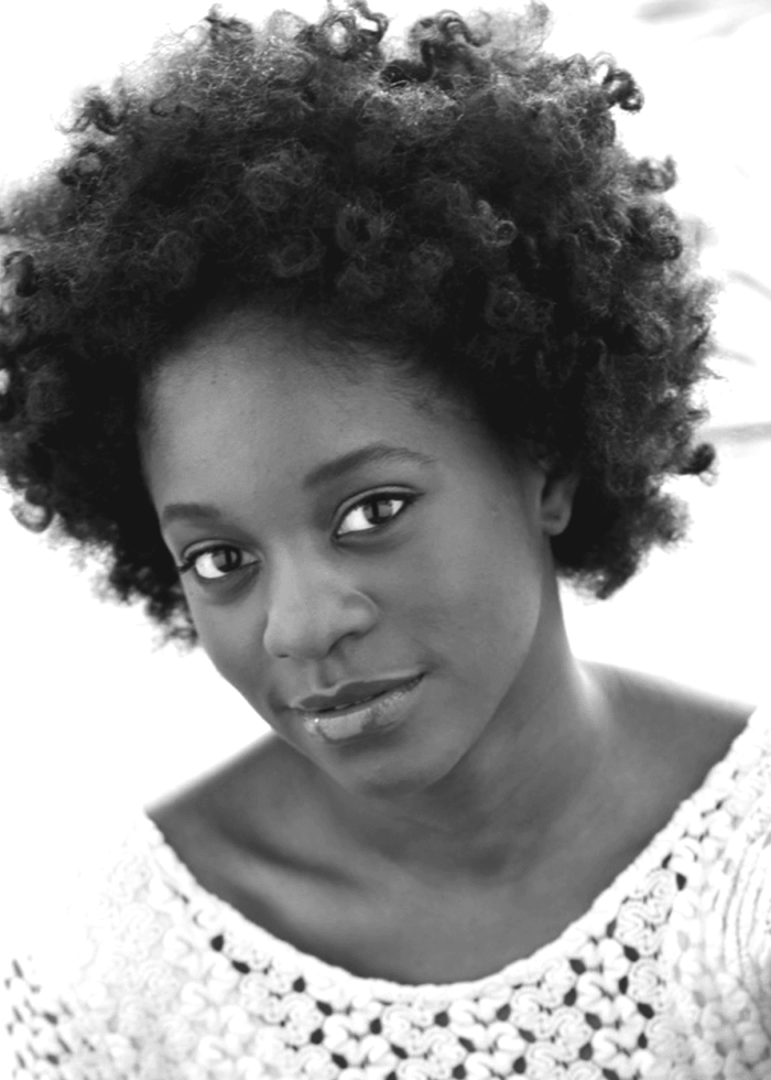 Black and white portrait of a woman with curly hair, looking at the camera.