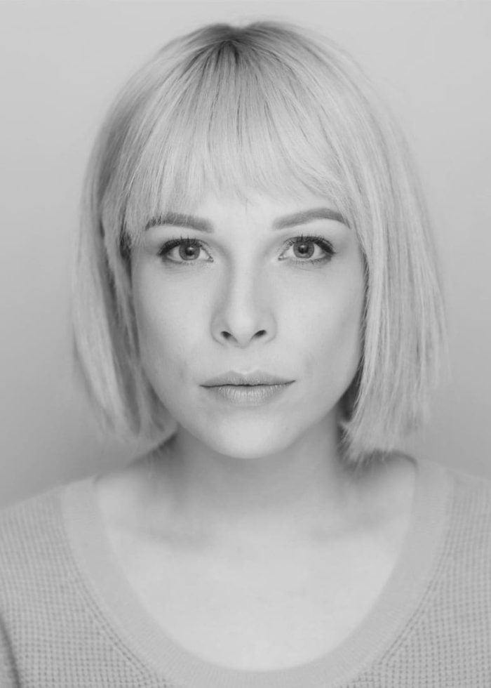 Lauren Marcus portrait with blonde bob and bangs, looking directly at the camera.