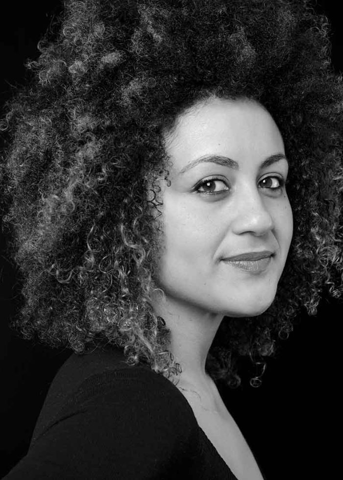 Black and white portrait of a woman with curly hair, smiling slightly.
