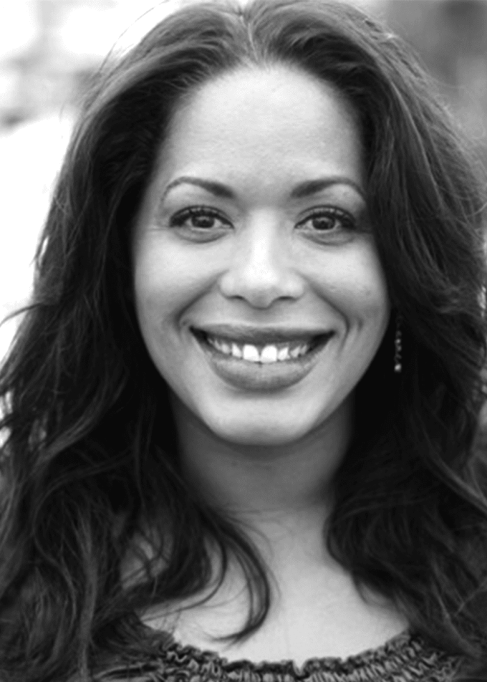 Liza Colón-Zayas smiles directly at the camera with long dark hair.