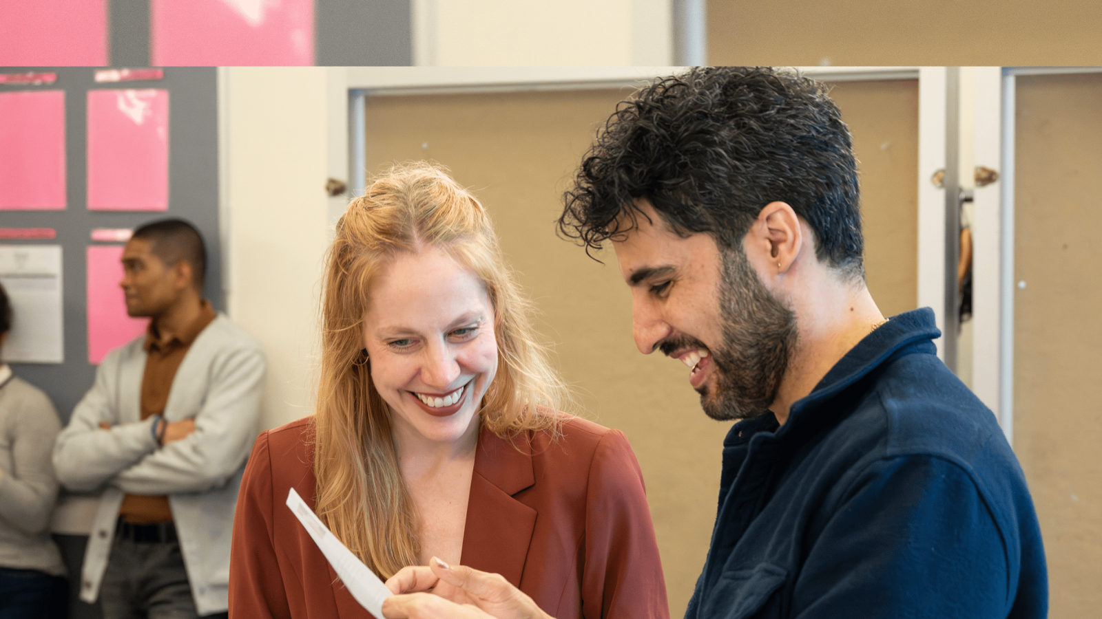 Two colleagues smiling while reviewing a document together.