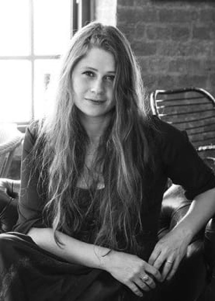 Black and white portrait of playwright Lucy Kirkwood, seated indoors.