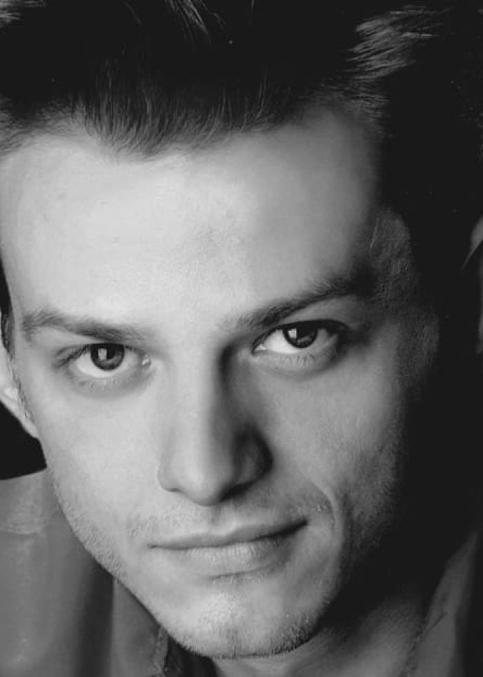 Black and white headshot of a man with dark hair and intense gaze