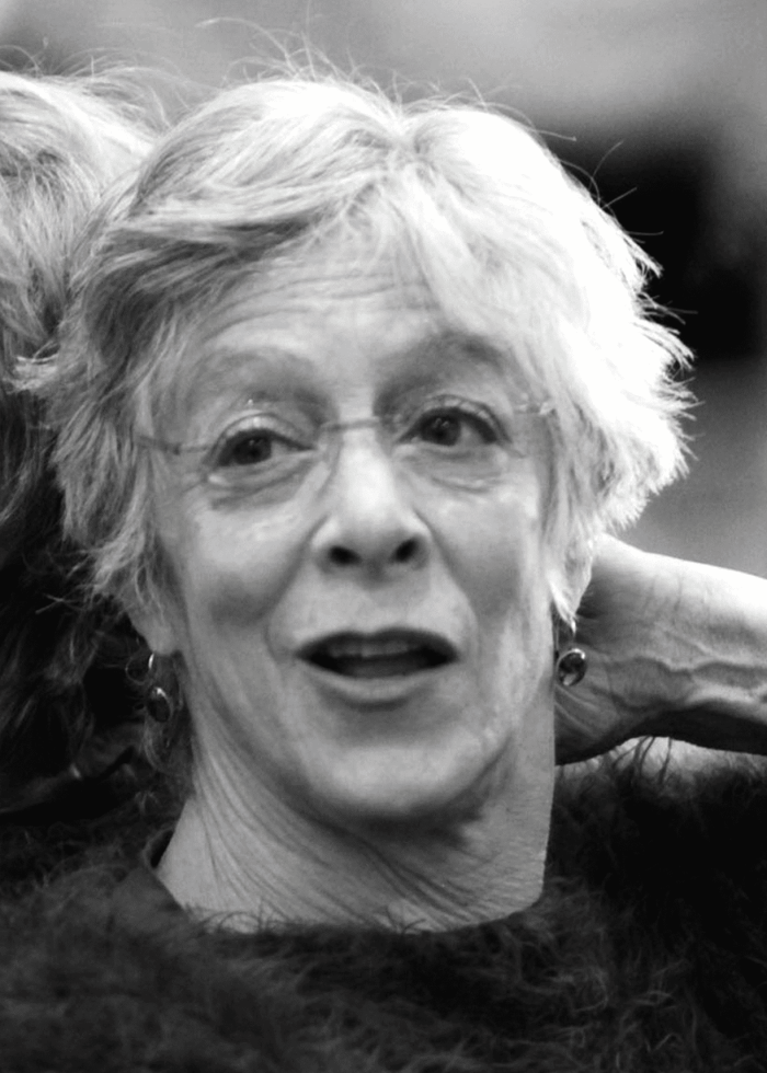 Martha Clarke, portrait in black and white, wearing glasses and earrings