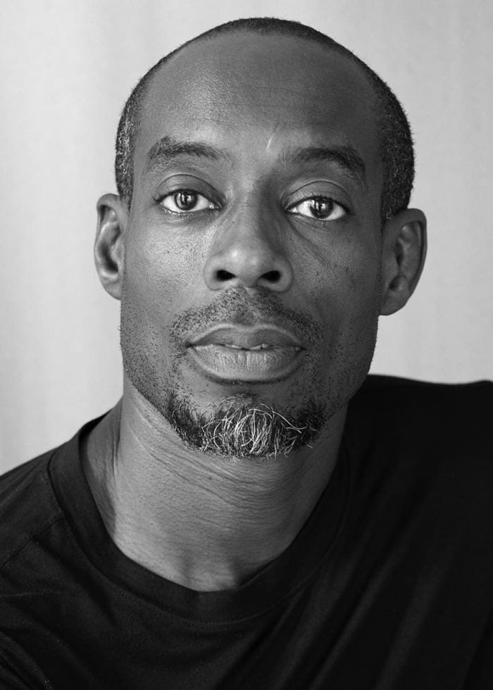 Mel Semé portrait in black and white, looking directly at the camera.