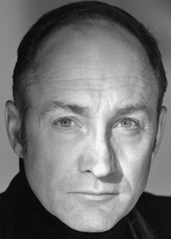 Michael McElhatton, actor, in a black and white headshot, looking directly at the camera.