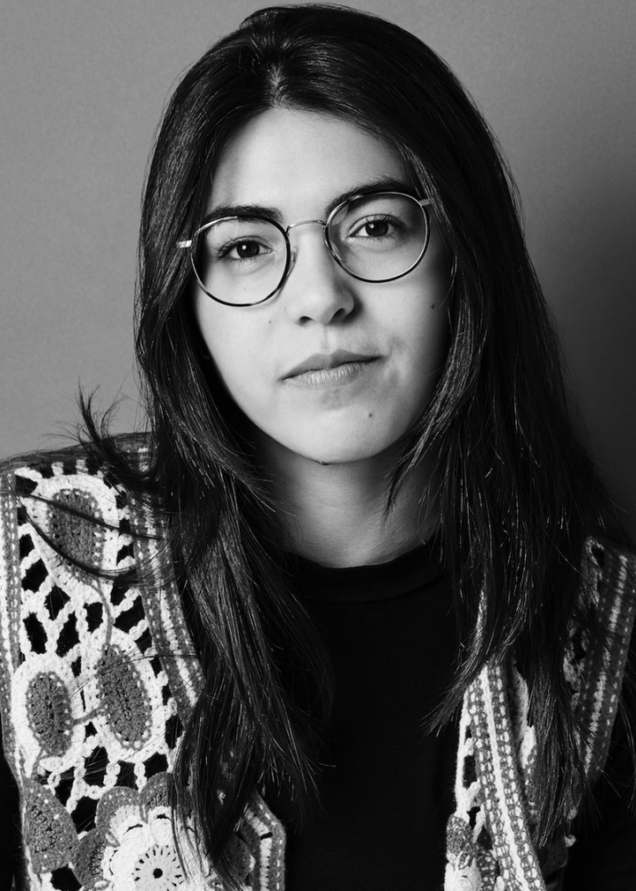 Miranda Cornell in black and white portrait, wearing glasses and a crochet vest.
