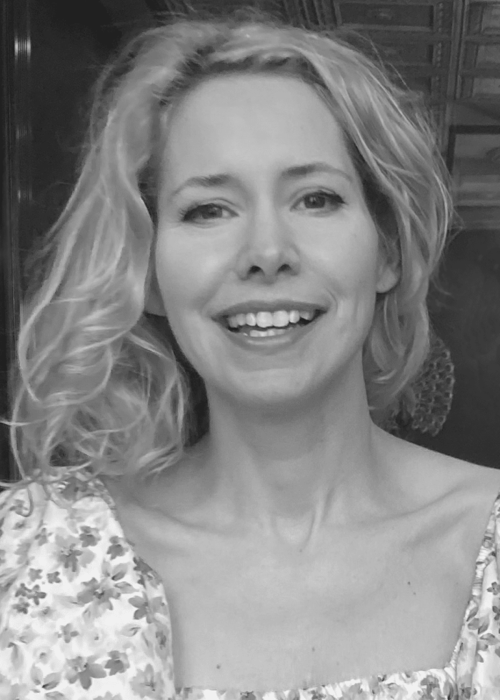 Nellie McKay smiles, wearing a floral dress.