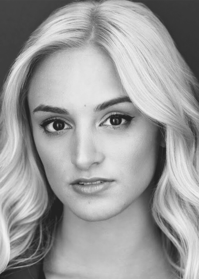 Black and white headshot of Nicole Medoro with blonde hair and dark eyeliner.