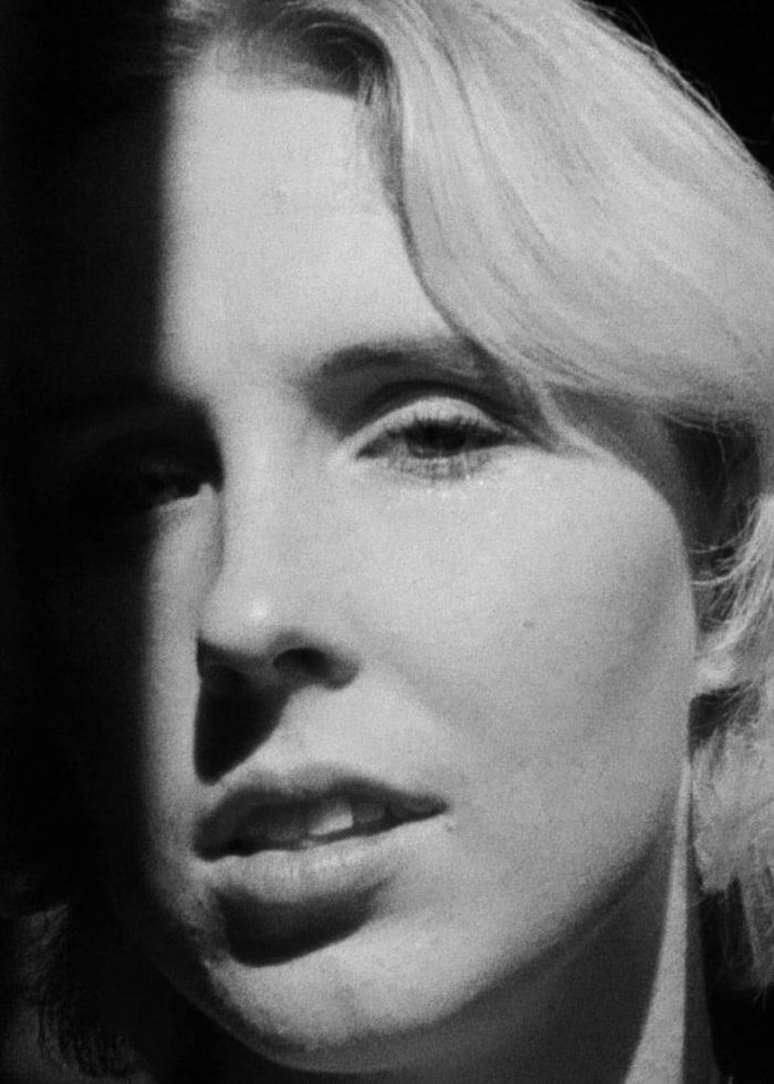 Close-up portrait of a woman with light hair, partially in shadow.