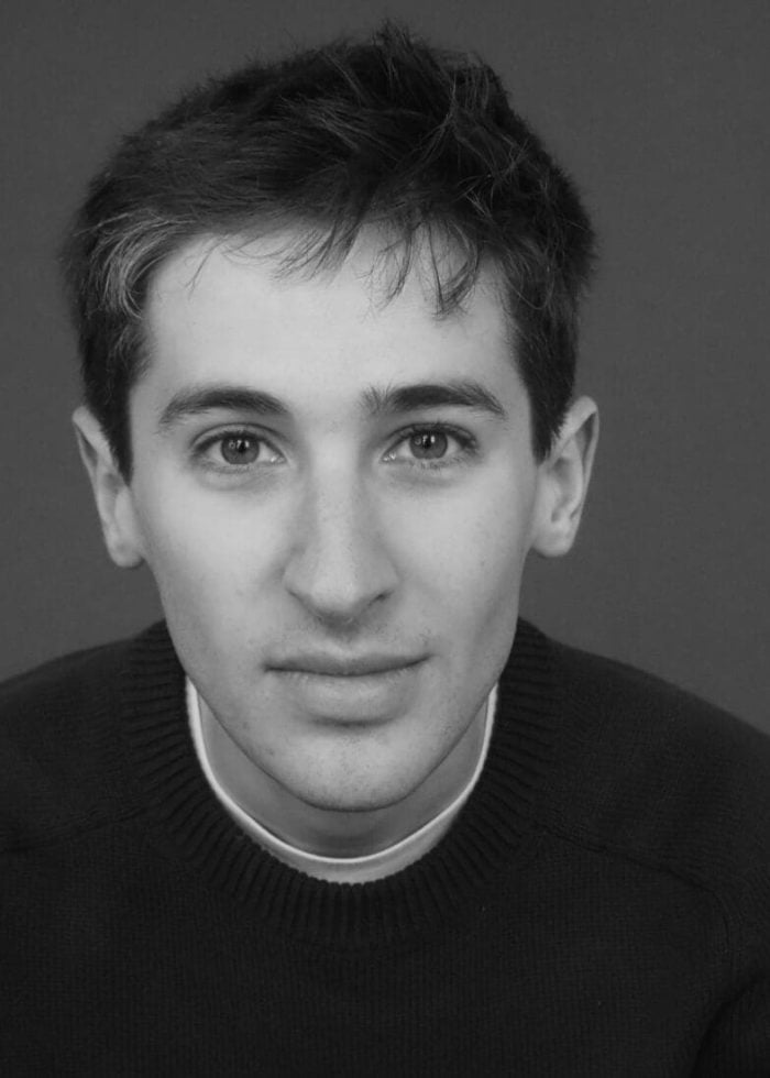 Black and white portrait of actor Noah Robbins looking directly at the camera.