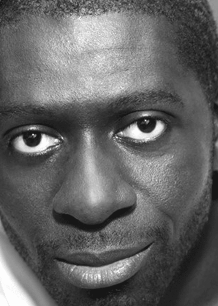 Close-up portrait of Oberon K. A. Adjepong, smiling with a subtle expression.