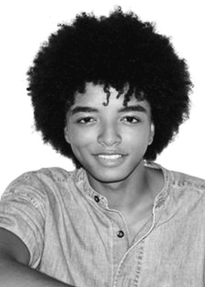 Odiseas-Georgiadis-Headshot Young man with afro smiling, wearing a denim shirt.
