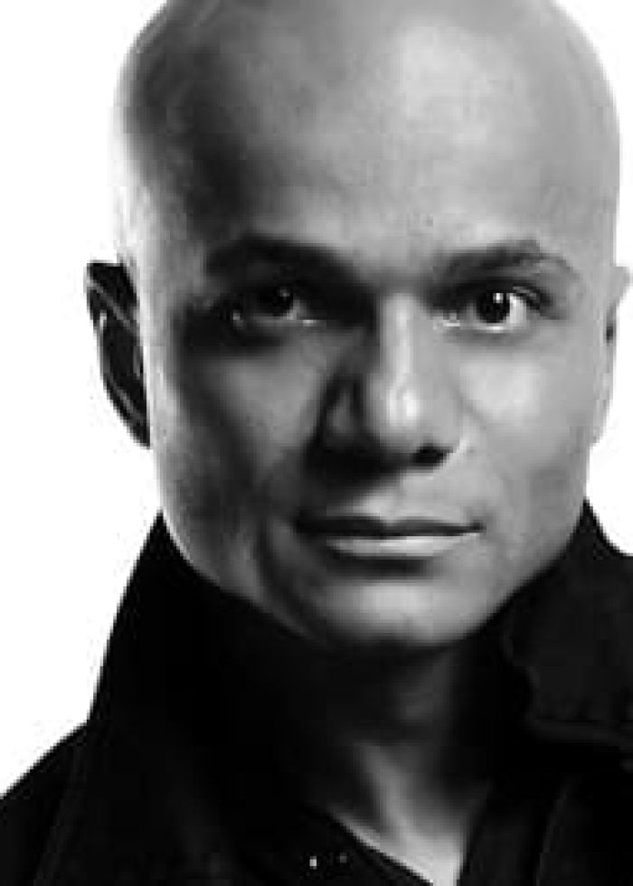 Omar Sangare, bald man in black shirt, looking at the camera