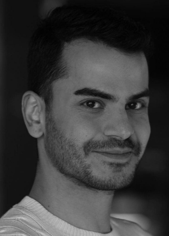 Omer Abbas Salem smiling, looking at the camera, with a beard and dark hair.