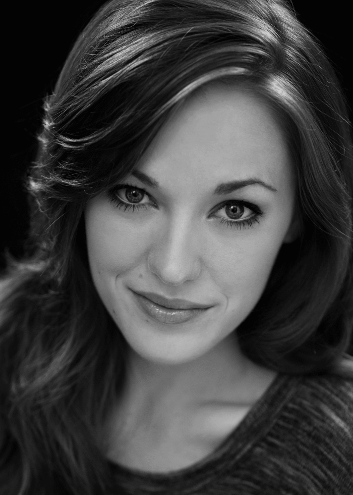 Laura Osnes, close-up headshot, smiling with long, wavy hair in black and white.